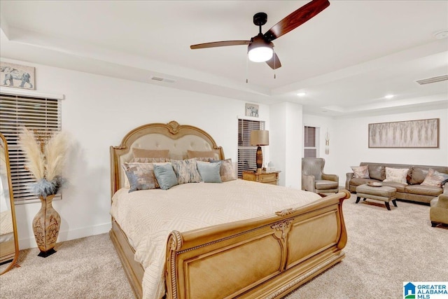 carpeted bedroom with ceiling fan and a raised ceiling