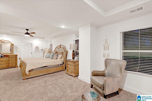 bedroom featuring a raised ceiling, light colored carpet, and ceiling fan