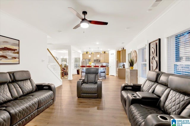 living room with crown molding, ceiling fan, and light wood-type flooring