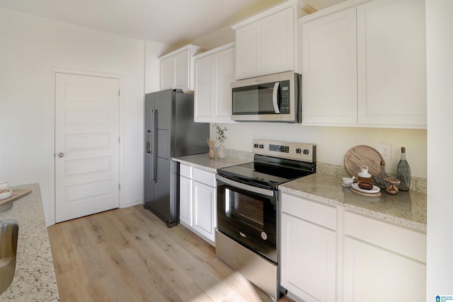 kitchen featuring light stone counters, light hardwood / wood-style flooring, white cabinets, and appliances with stainless steel finishes