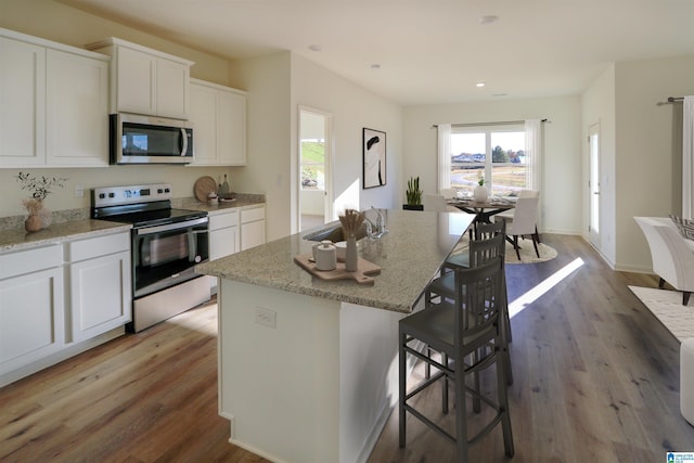 kitchen featuring sink, white cabinetry, a center island with sink, appliances with stainless steel finishes, and light stone countertops