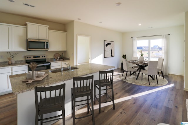 kitchen featuring sink, appliances with stainless steel finishes, white cabinetry, a kitchen breakfast bar, and an island with sink