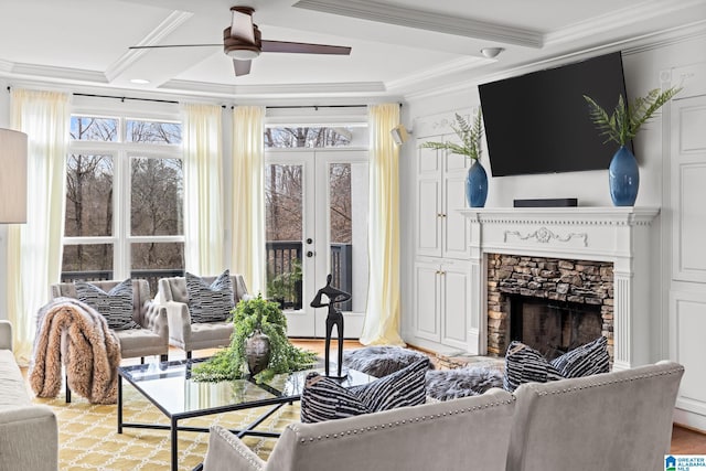 living room with crown molding, a stone fireplace, beam ceiling, and ceiling fan