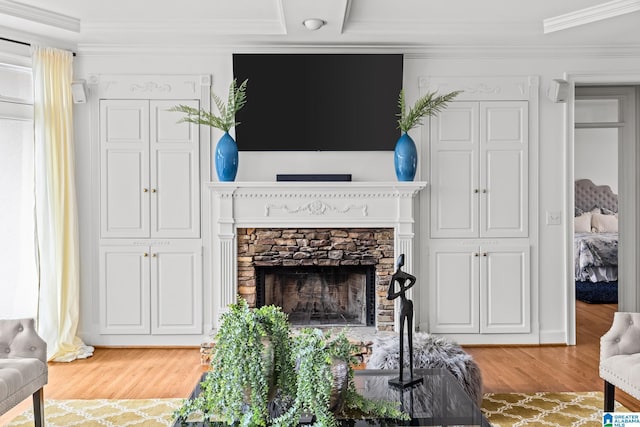 living room featuring a stone fireplace, ornamental molding, and hardwood / wood-style flooring