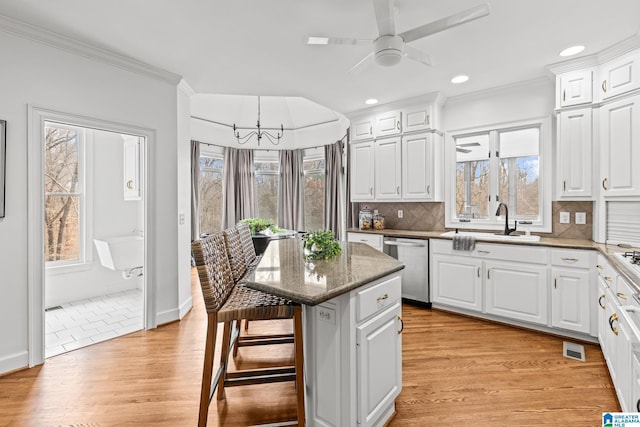 kitchen featuring a breakfast bar, dishwasher, a center island, white cabinets, and light wood-type flooring