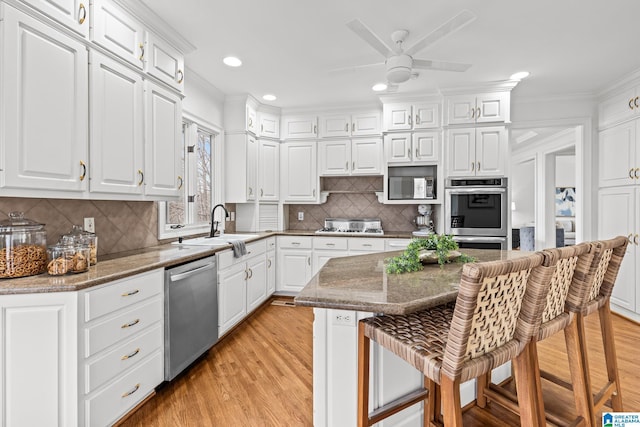 kitchen featuring a kitchen island, white cabinetry, appliances with stainless steel finishes, and a breakfast bar area