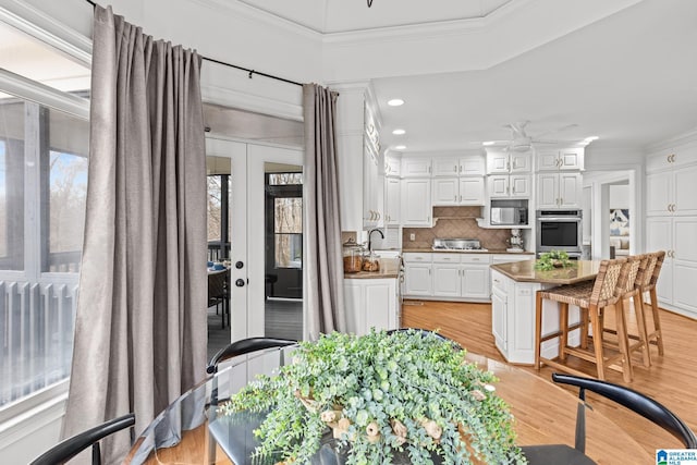 kitchen featuring white cabinetry, backsplash, ornamental molding, a kitchen island, and built in microwave