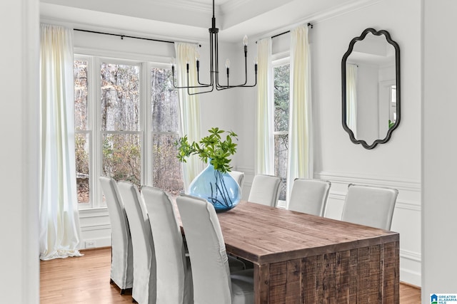 dining area with crown molding, an inviting chandelier, and light wood-type flooring