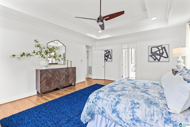 bedroom with ensuite bathroom, wood-type flooring, ceiling fan, a tray ceiling, and crown molding