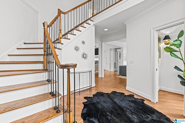 stairway with hardwood / wood-style floors, ornamental molding, and a high ceiling