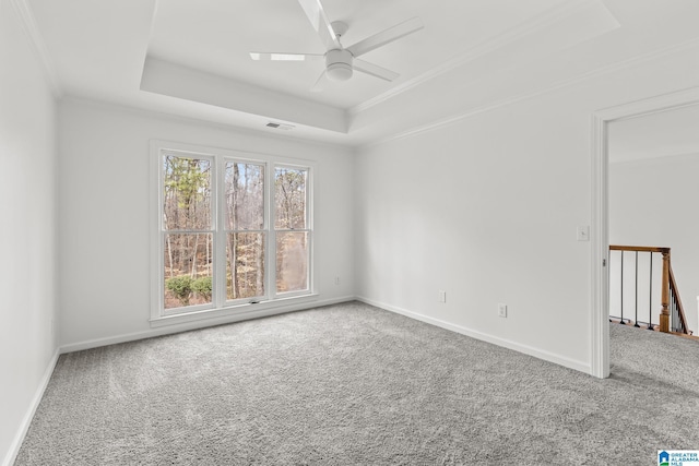 carpeted empty room with crown molding, a raised ceiling, and ceiling fan