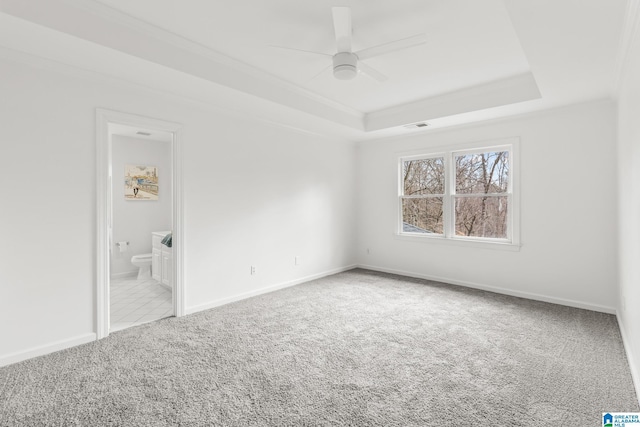 spare room featuring ceiling fan, light colored carpet, a tray ceiling, and crown molding