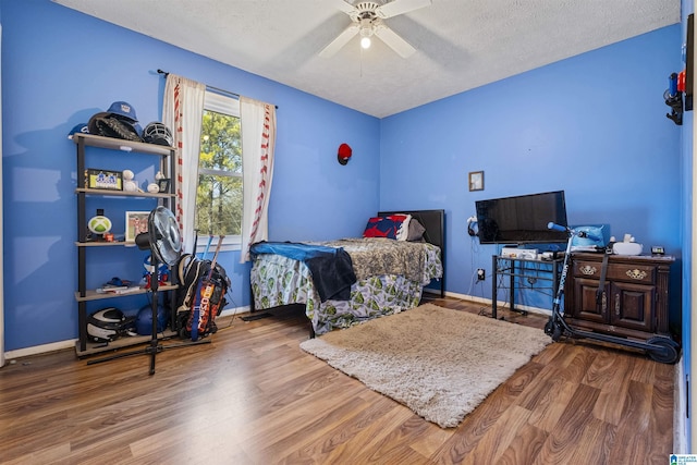 bedroom featuring ceiling fan, wood-type flooring, and a textured ceiling