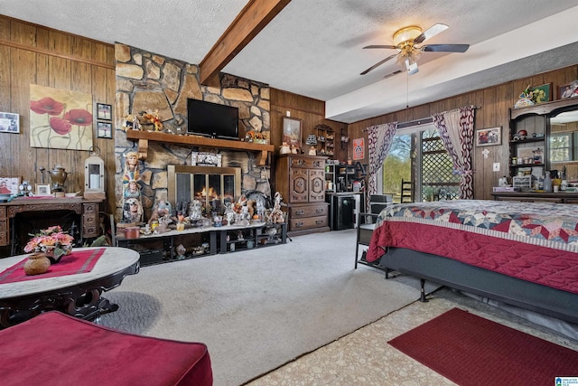 carpeted bedroom with beam ceiling, a stone fireplace, wooden walls, and a textured ceiling