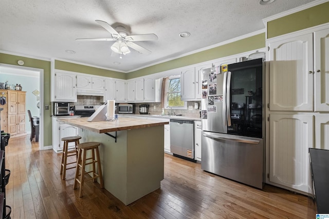 kitchen featuring a kitchen island, wooden counters, white cabinets, and appliances with stainless steel finishes