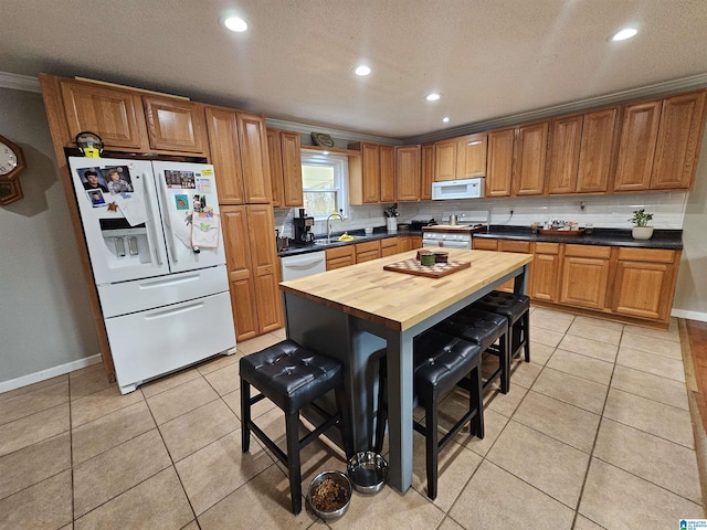 kitchen featuring wood counters, sink, white appliances, and light tile patterned floors