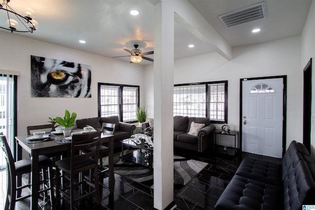 living room with beamed ceiling and ceiling fan with notable chandelier