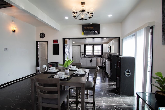 dining area with an inviting chandelier and stacked washer and clothes dryer