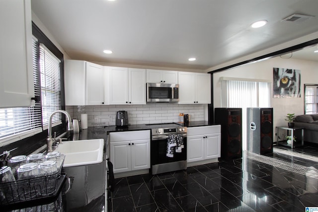 kitchen featuring tasteful backsplash, white cabinetry, appliances with stainless steel finishes, and sink