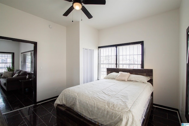 bedroom with ceiling fan, a closet, and dark tile patterned floors