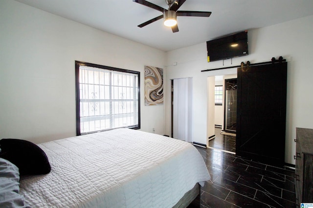 bedroom featuring multiple windows, a barn door, and ceiling fan