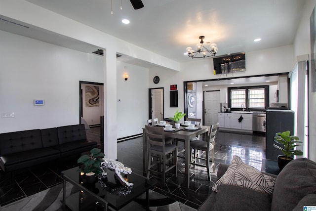 dining area with ceiling fan with notable chandelier, stacked washer and clothes dryer, and sink