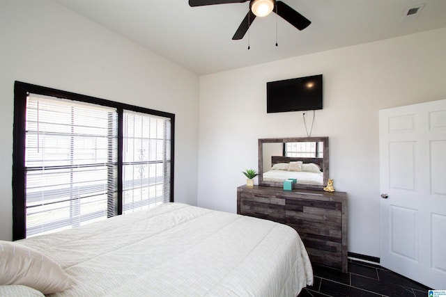 bedroom with multiple windows, dark tile patterned flooring, and ceiling fan