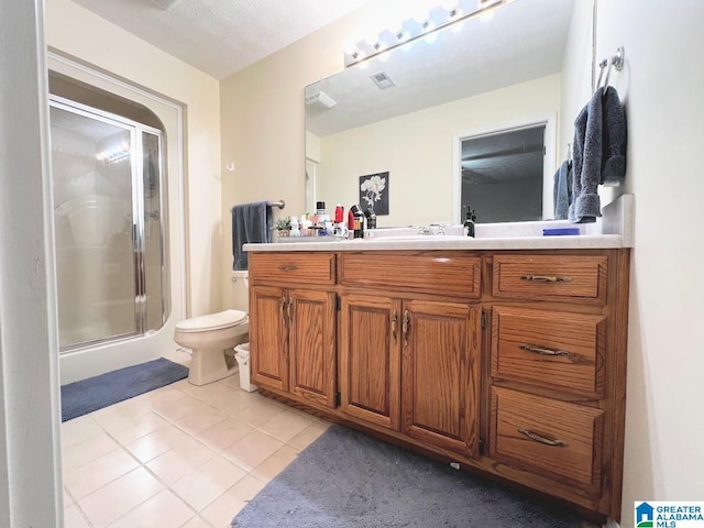 bathroom with a shower with door, vanity, tile patterned floors, and toilet