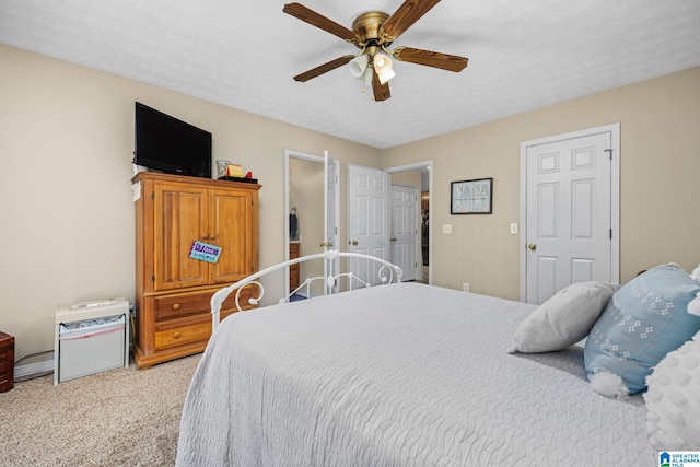 bedroom with ceiling fan, light colored carpet, and a textured ceiling