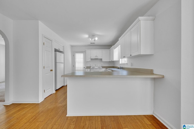 kitchen with white appliances, kitchen peninsula, sink, and white cabinets