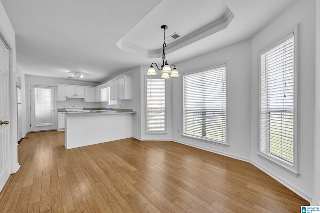 kitchen featuring white cabinetry, pendant lighting, kitchen peninsula, and a tray ceiling