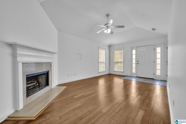 unfurnished living room with vaulted ceiling, light hardwood / wood-style floors, a premium fireplace, and ceiling fan