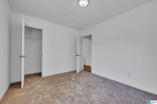 unfurnished bedroom with light colored carpet and a closet