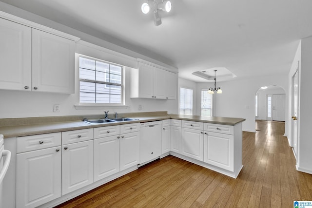 kitchen with decorative light fixtures, dishwasher, sink, white cabinets, and kitchen peninsula