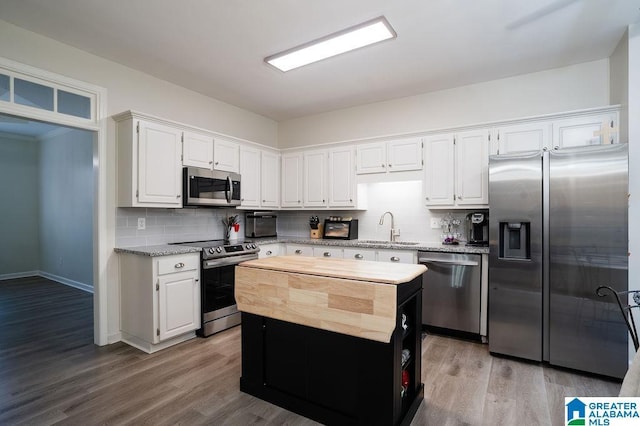 kitchen featuring white cabinetry, sink, backsplash, a center island, and stainless steel appliances