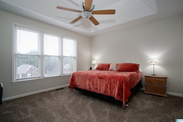 carpeted bedroom featuring ceiling fan and a tray ceiling