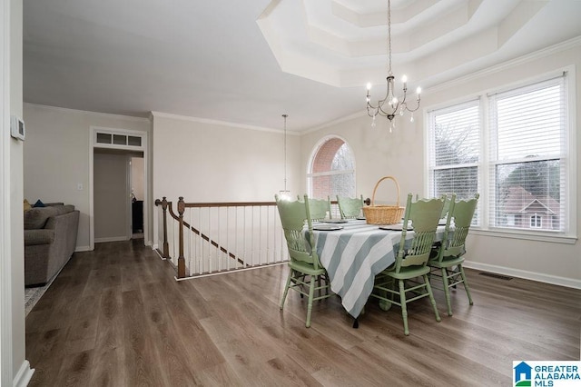 dining room featuring an inviting chandelier, ornamental molding, a tray ceiling, and hardwood / wood-style floors