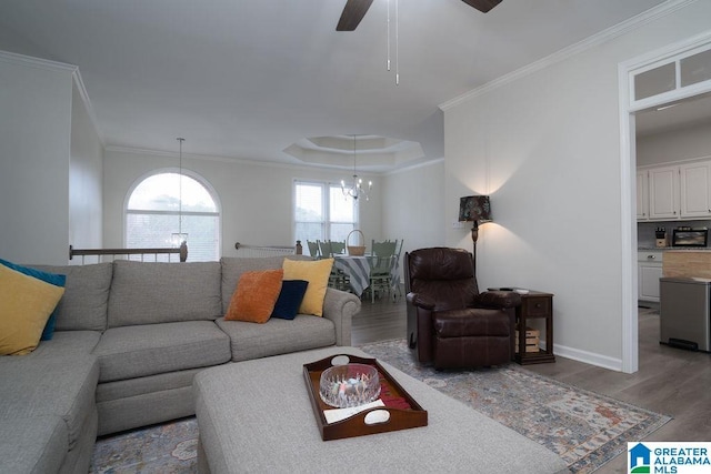 living room featuring a tray ceiling, hardwood / wood-style flooring, ornamental molding, and ceiling fan