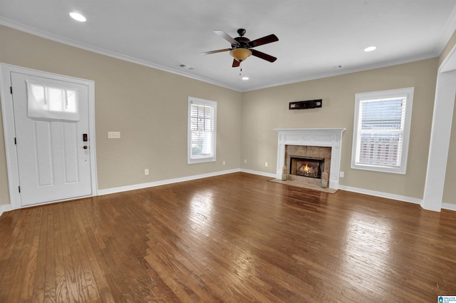 unfurnished living room with dark wood-type flooring, ceiling fan, ornamental molding, and a fireplace