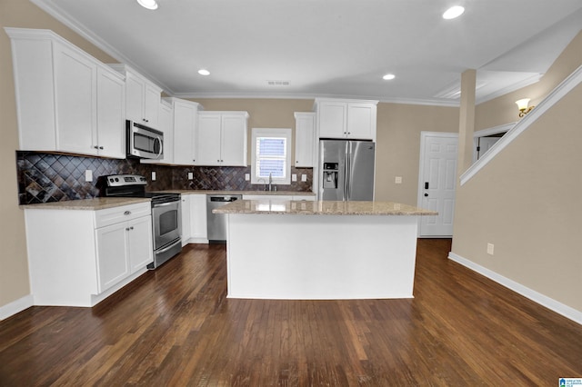 kitchen featuring dark hardwood / wood-style floors, white cabinets, a center island, stainless steel appliances, and light stone countertops