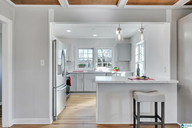 kitchen featuring gray cabinetry, a wealth of natural light, a breakfast bar area, and appliances with stainless steel finishes