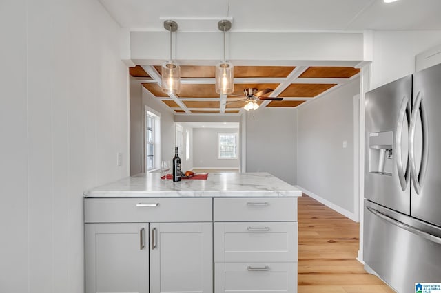 kitchen featuring hanging light fixtures, coffered ceiling, light stone counters, stainless steel fridge with ice dispenser, and light hardwood / wood-style flooring