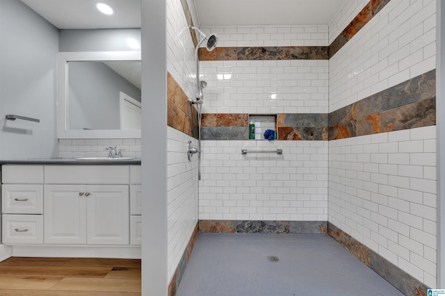 bathroom featuring a tile shower, vanity, and hardwood / wood-style floors