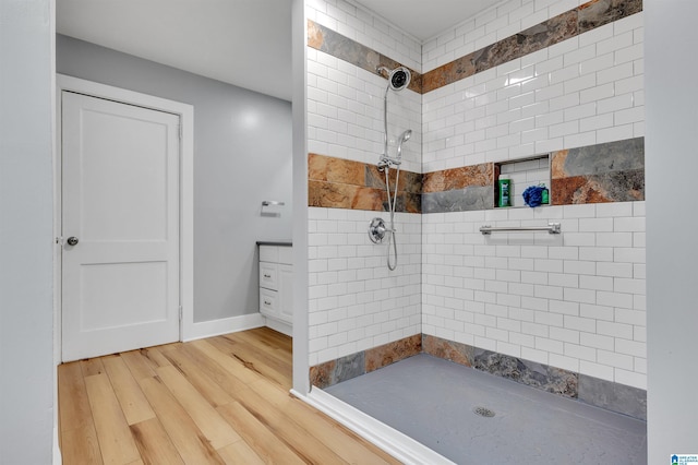 bathroom with tiled shower and hardwood / wood-style floors