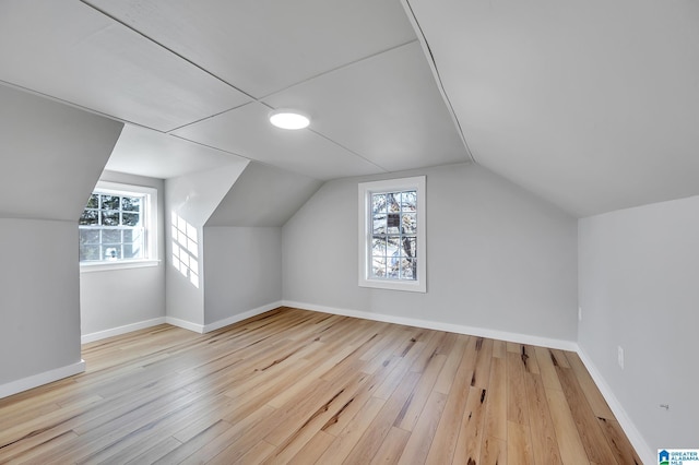 additional living space featuring vaulted ceiling, plenty of natural light, and light hardwood / wood-style flooring