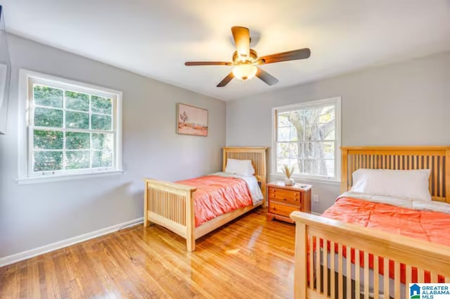 bedroom with multiple windows, ceiling fan, and light hardwood / wood-style floors