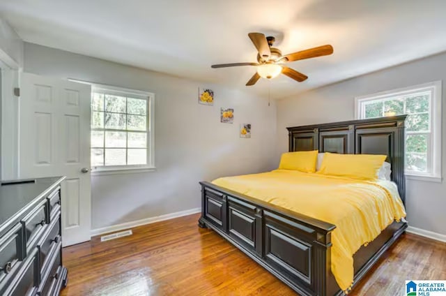 bedroom featuring multiple windows, hardwood / wood-style floors, and ceiling fan