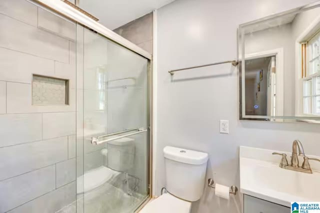 bathroom featuring a shower with door, vanity, and toilet