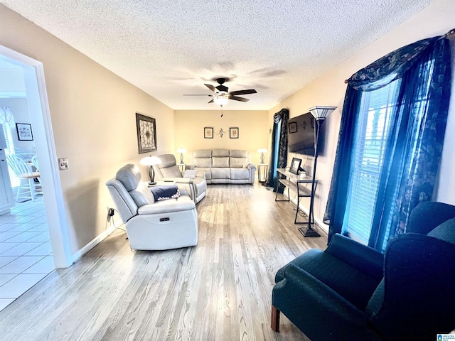 living room featuring ceiling fan, a textured ceiling, and light wood-type flooring