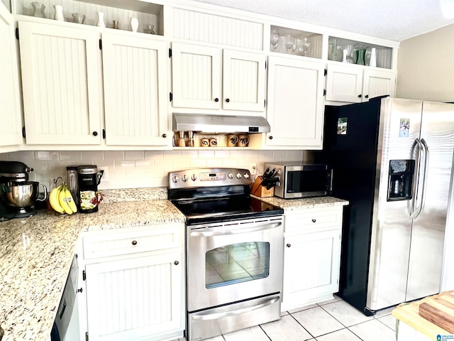 kitchen with appliances with stainless steel finishes, white cabinets, decorative backsplash, light tile patterned floors, and light stone counters